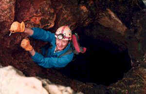 Thumbnail of a Photo showing a man descending by rope ladder into a cave.