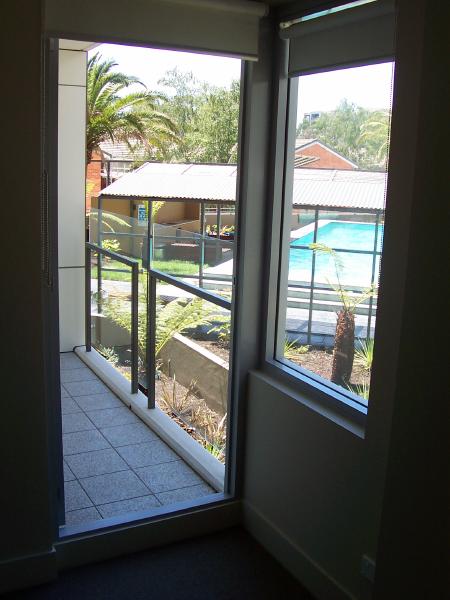 Bedroom 1 door to rear balcony and view to central pool area.